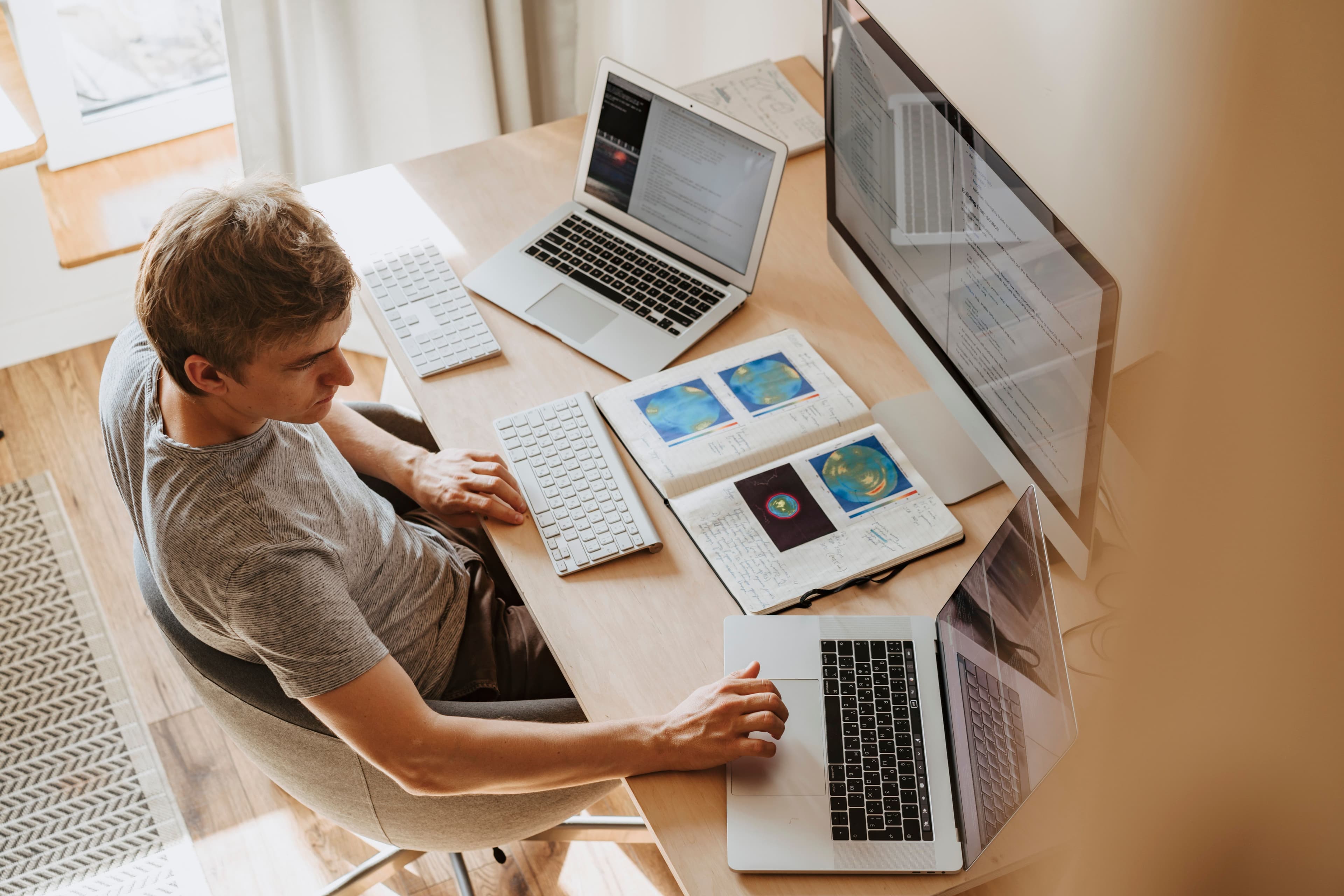 Webentwickler am Arbeitsplatz mit mehreren Bildschirmen und Planungsunterlagen